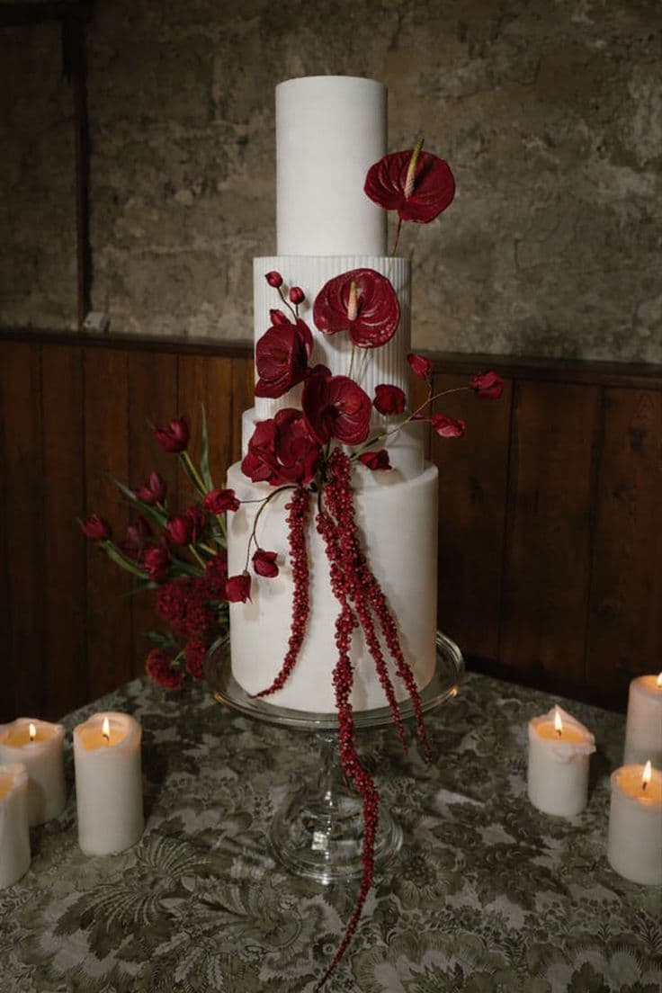 A white wedding cake dressed with deep red anthurium