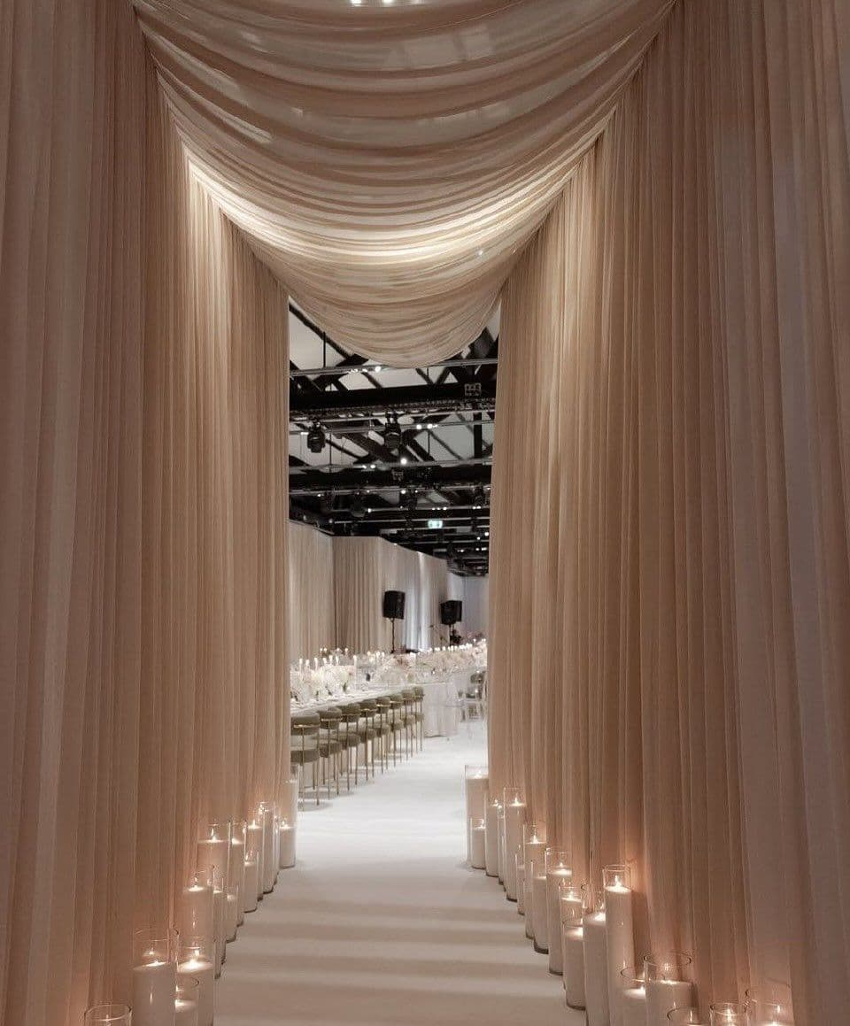 A draped aisle lined with pillar candles leading to the reception