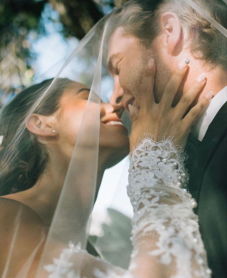 A couple close beneath a veil in soft daylight