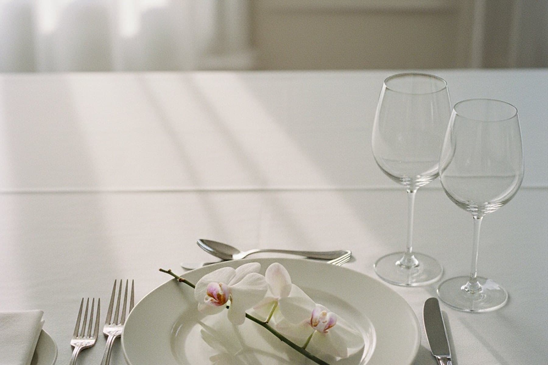 A dinner table set with crystal glasses in soft light