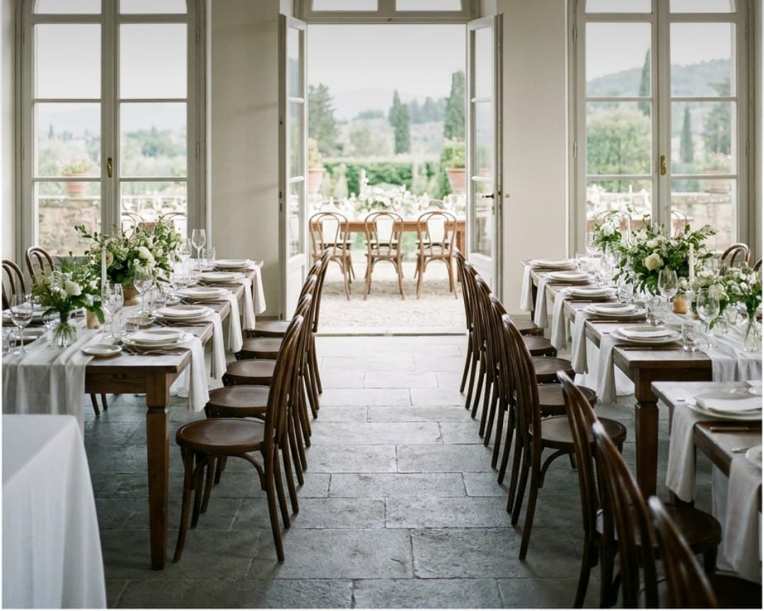 A long table set between arched doors opening onto a valley
