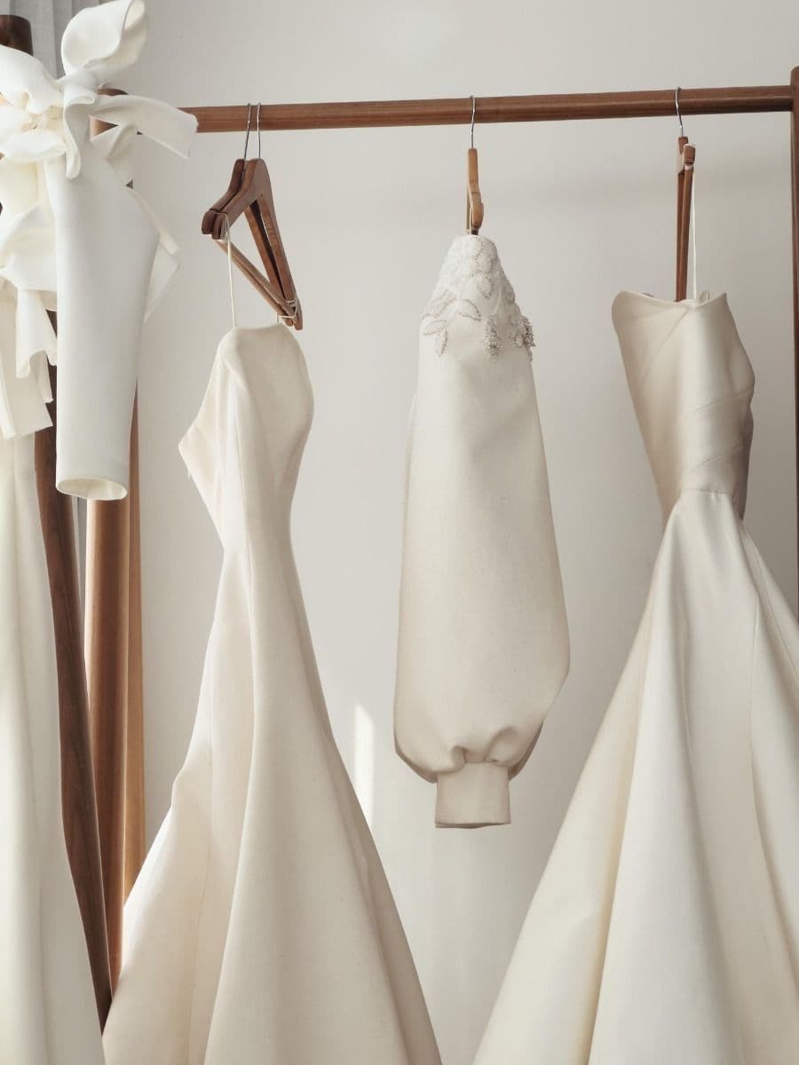 Wedding gowns hanging on a wooden rail in soft light