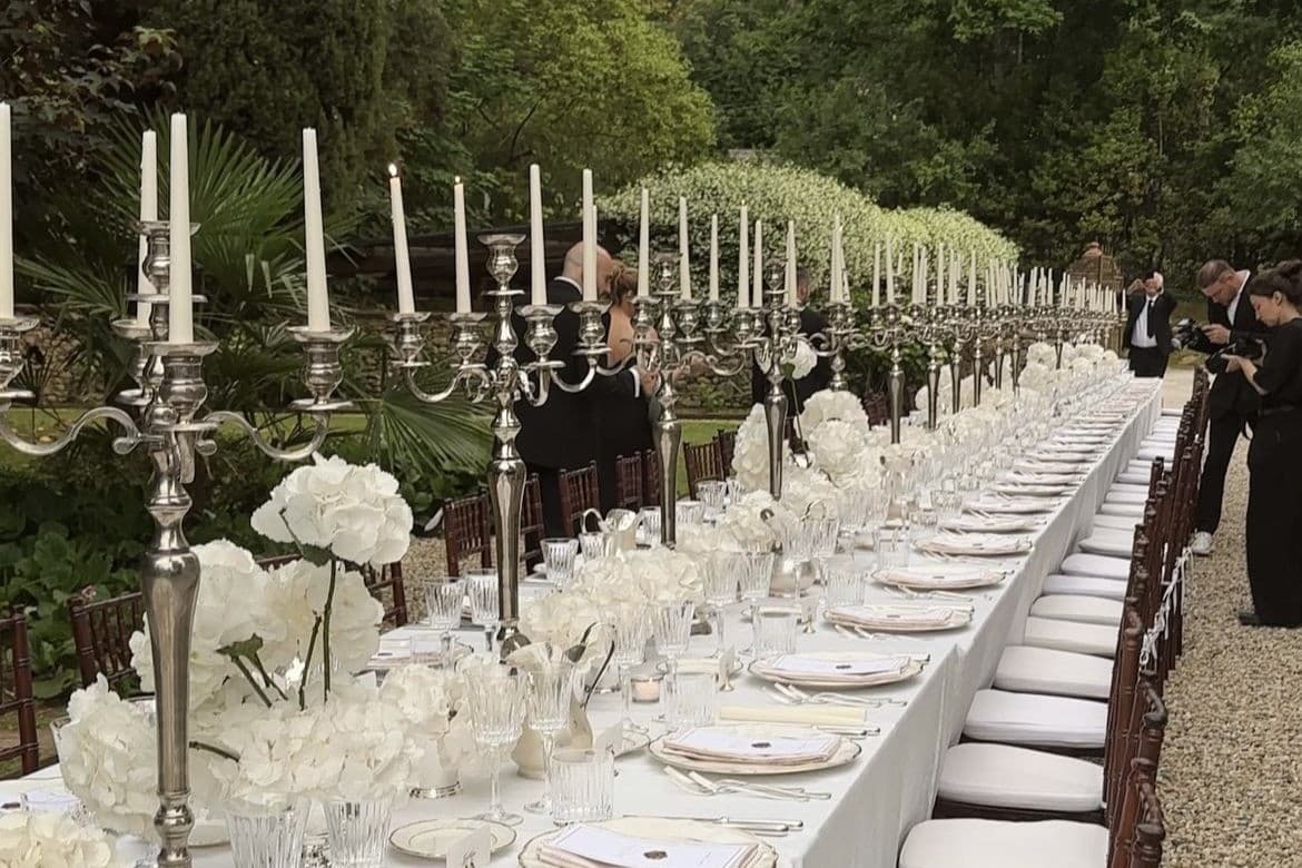 A long candlelit table set for dinner in a garden