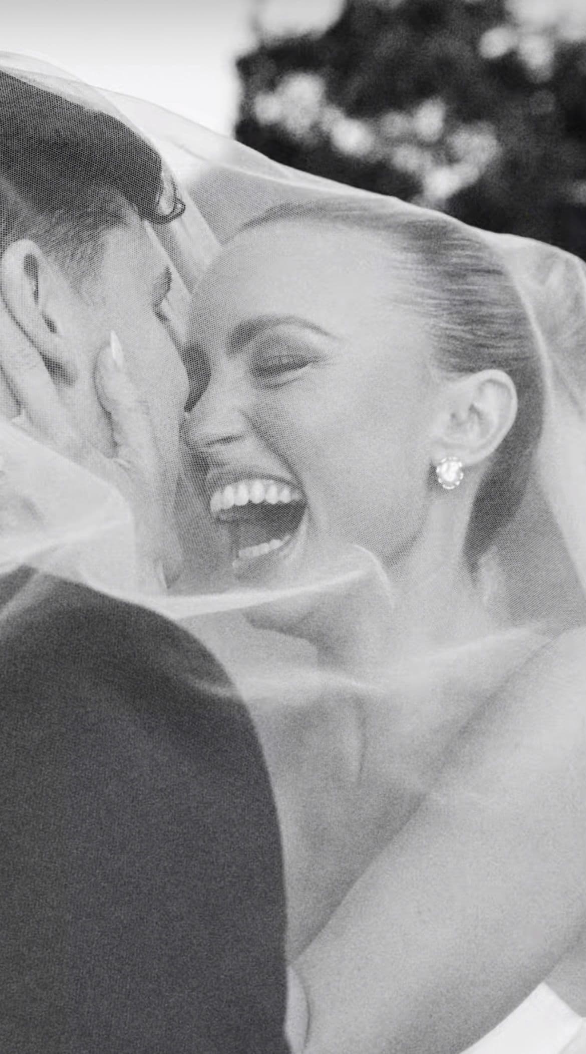 A couple laughing beneath a veil in black and white