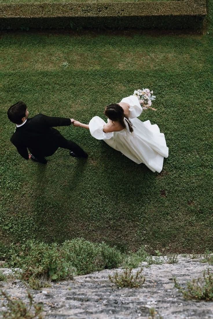 A couple crossing a green lawn hand in hand, seen from above