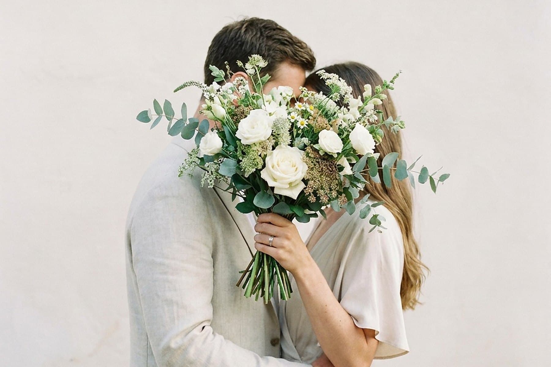 A couple embracing, her bouquet held between them