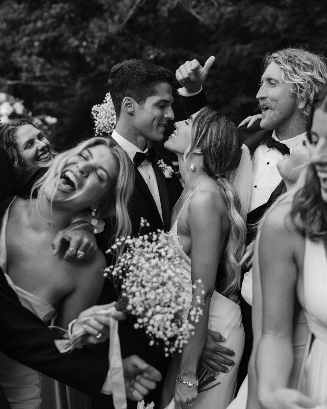 Guests crowded around the bride and groom mid laugh, photographed in black and white