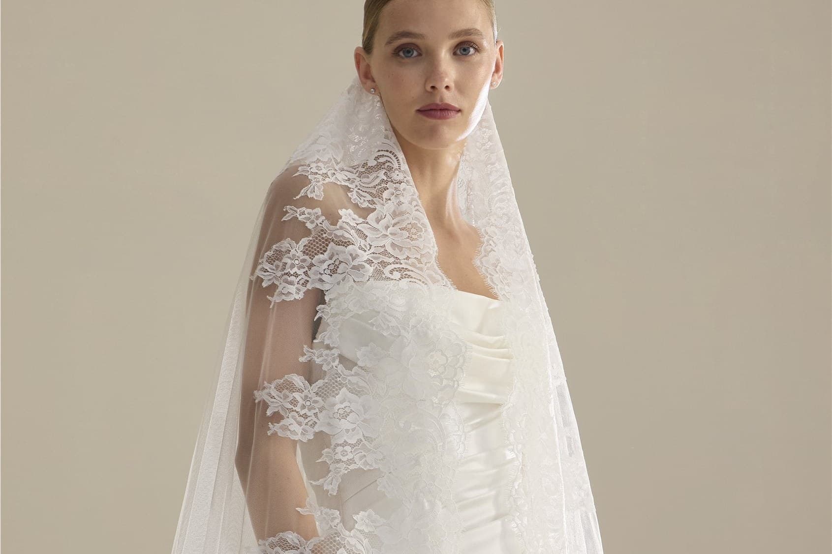 A bride in a lace-edged cathedral veil falling over her shoulder